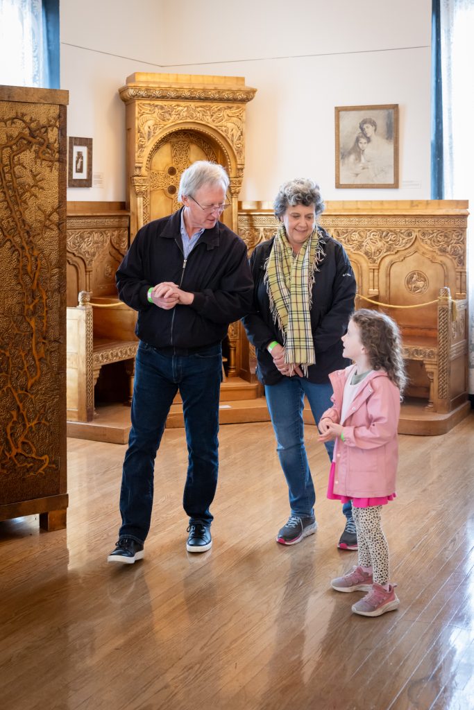 Centennial Time Capsule Burial Ceremony 13 Grandfather and grandmother looking at art with their young granddaughter inside a gallery while visiting Maryhill Museum of Art